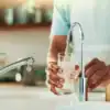 Lavabo de cuisine avec robinet en action pour laver un verre d'eau claire, concept de nettoyage et de désinfection de qualité, boutique Diproclean, produits professionnels pour l'entretien domestique et commercial.