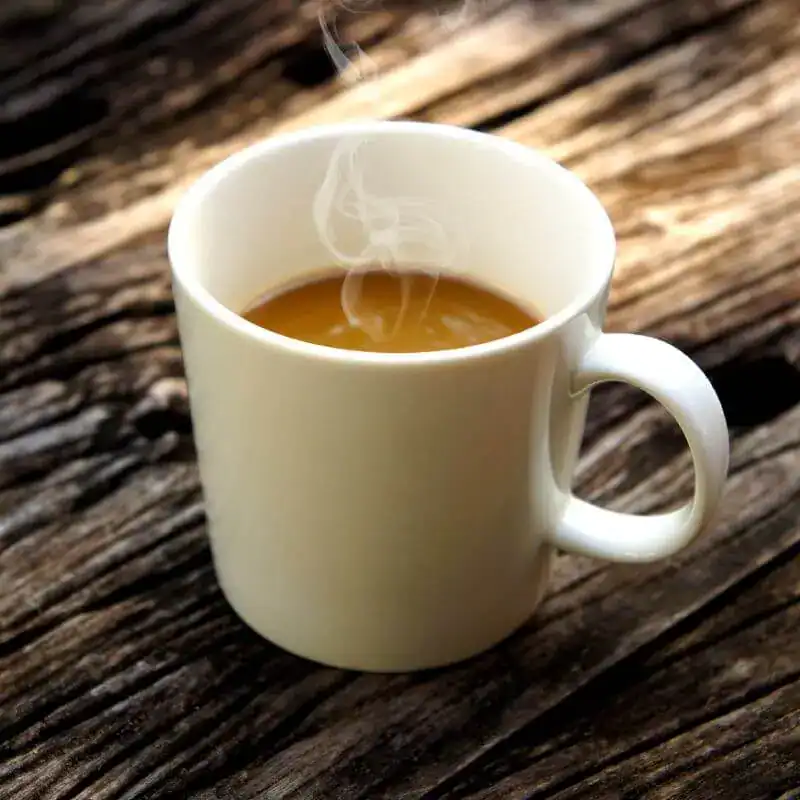 Chaude tasse de café fumant sur une vieille planche en bois, idéale pour un moment de détente ou petit-déjeuner. Parfait pour réveiller vos matins avec saveur et confort.