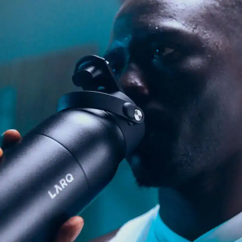 Aperçu d’un homme buvant dans une bouteille d’eau réutilisable LARQ, dans un environnement moderne et dynamique.